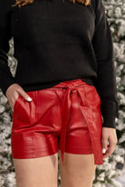 faux leather material, the signature elastic band in the back, zip & button closures, side pockets, & a non-removable tie