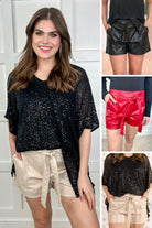 sleek faux leather shorts with zip and button closure, side pockets, a non-removable tie detail, and an elastic back waistband in black, red, and taupe