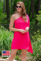 a magenta one-shoulder mini dress with an asymmetrical neckline and a draping, billowy body creating a relaxed silhouette with a MADE IN USA watermark in bottom lefthand corner