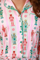 a soft two-piece pajama set (long sleeves and pants) with alternating nutcracker, peppermint, and aqua-and-pink stripe patterns, sweet ruffle hem detail, coordinating aqua trim accents, a decorative aqua faux belt, and a comfy elastic waistband for an easy, relaxed fit