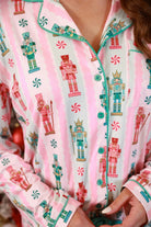 a soft two-piece pajama set (long sleeves and pants) with alternating nutcracker, peppermint, and aqua-and-pink stripe patterns, sweet ruffle hem detail, coordinating aqua trim accents, a decorative aqua faux belt, and a comfy elastic waistband for an easy, relaxed fit