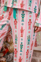 a soft two-piece pajama set (long sleeves and pants) with alternating nutcracker, peppermint, and aqua-and-pink stripe patterns, sweet ruffle hem detail, coordinating aqua trim accents, a decorative aqua faux belt, and a comfy elastic waistband for an easy, relaxed fit
