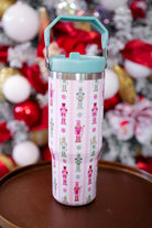 30-ounce striped pale pink insulated tumbler with a variety of whimsical multicolor pastel nutcrackers and peppermint swirls on white lace with a mint sturdy built-in handle, lid, and straw complete with silver hardware