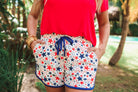mid-rise relaxed fit activewear shorts with side pockets and a tie waist drawstring with gold bead accents, designed on a patriotic star pattern print fabric, white base, and navy trim