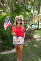 mid-rise relaxed fit activewear shorts with side pockets and a tie waist drawstring with gold bead accents, designed on a patriotic star pattern print fabric, white base, and navy trim