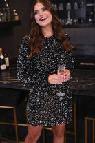 a black long balloon sleeve dress made of sparkly allover sequins, luxe velvet underlay, a keyhole accented upper back with button closure, a round neckline, and subtle elastic cuffs