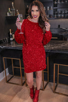 a red long balloon sleeve dress made of sparkly allover sequins, luxe velvet underlay, a keyhole accented upper back with button closure, a round neckline, and subtle elastic cuffs