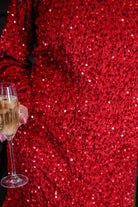 a red long balloon sleeve dress made of sparkly allover sequins, luxe velvet underlay, a keyhole accented upper back with button closure, a round neckline, and subtle elastic cuffs