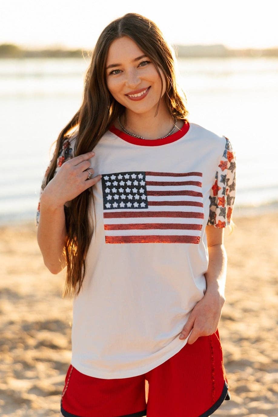 a high-stretch roomy-fit crew neck top with a sequin American flag front, lined star sleeves (red, white, and blue), red neckline trim, and a comfortable fit that runs large