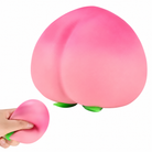 a pink ombré peach-shaped squishy toy with a soft touch texture, rounded fruit design, center groove, green leaf accent, and clear individual packaging