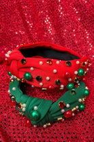 top knot adorned with jewel-tone beads, pearls, and rhinestones on velvet in green and red