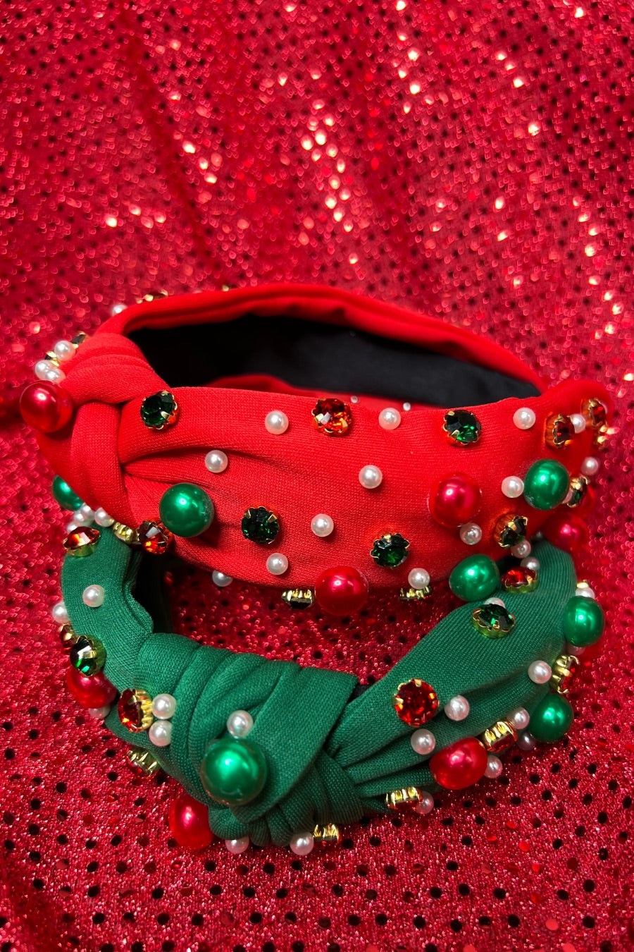 top knot adorned with jewel-tone beads, pearls, and rhinestones on velvet in green and red