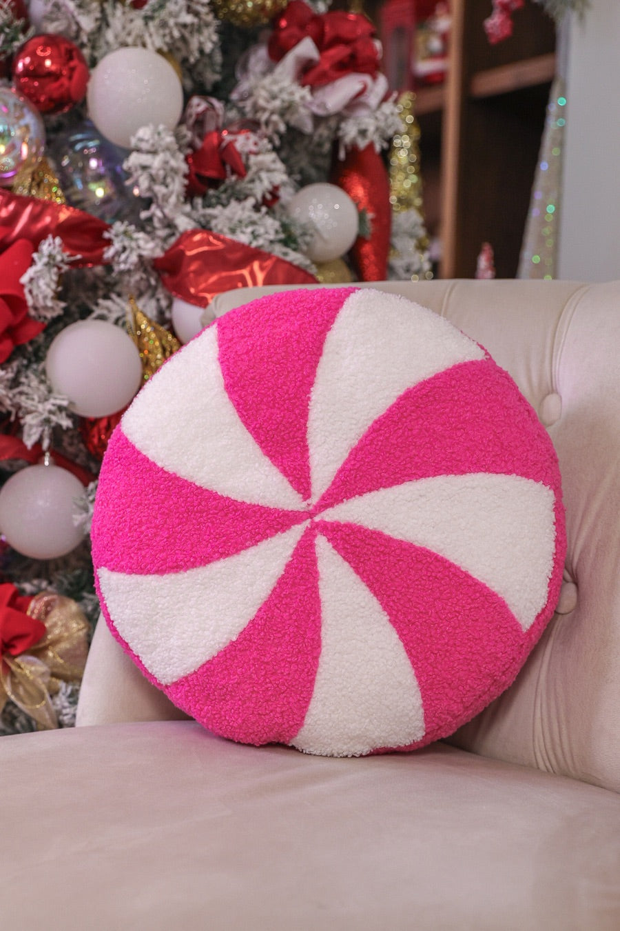 a round cushion with a bold hot pink and white peppermint swirl design on a soft, textured bouclé fabric