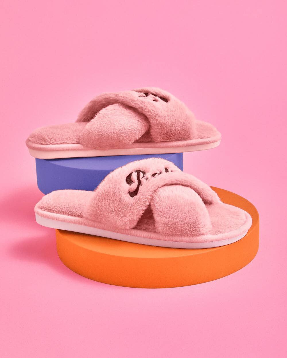 Pink slippers on colorful platforms against a pink background