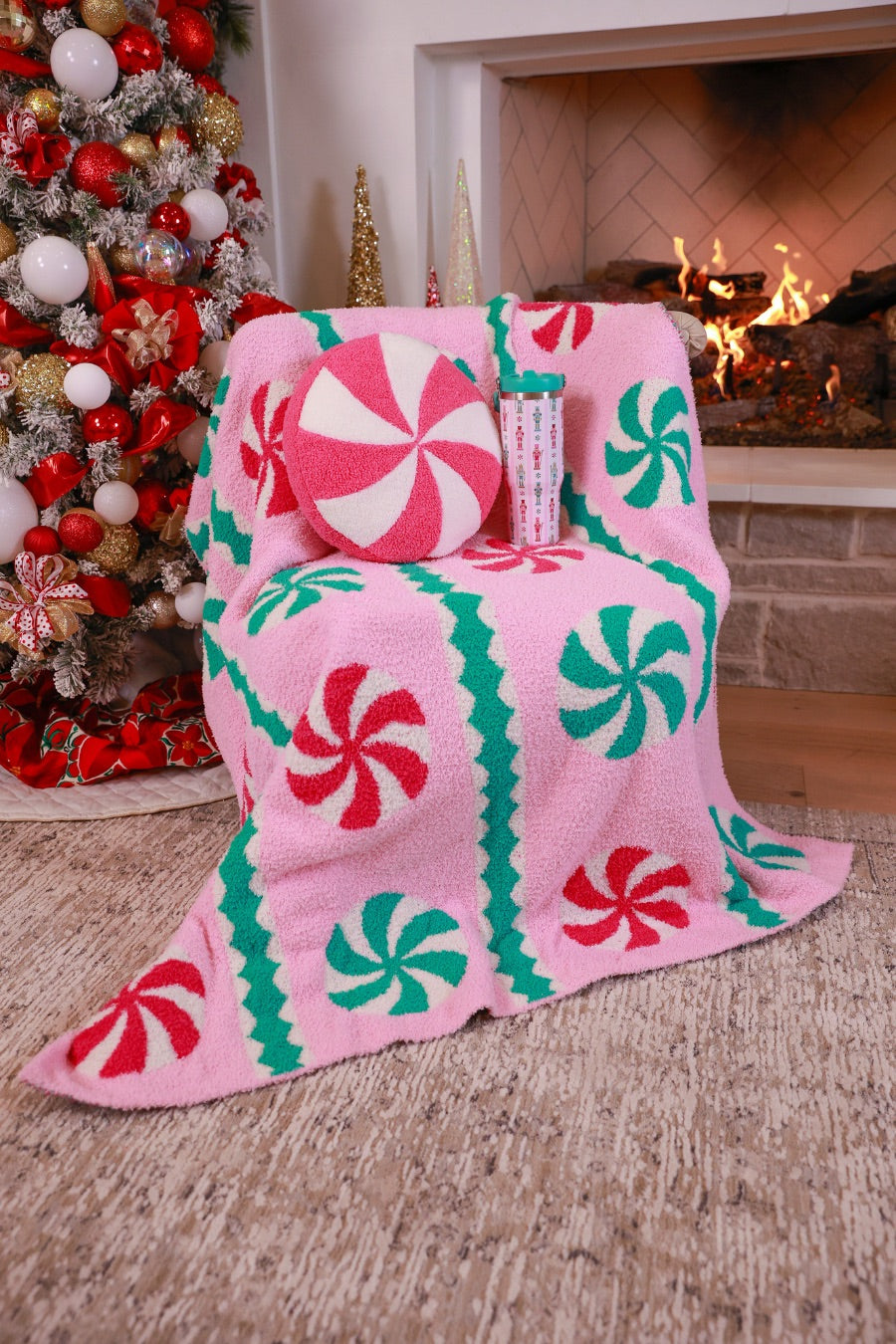 ultra-soft throw on a playful peppermint candy motifs dancing across a cotton candy pink background, framed with whimsical mint green and white scalloped stripes paired with our Pink Peppermint Pillow and Nutcracker Magic Travel Tumbler