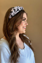 a soft purple fabric headband with black whimsical hat, bat, moon, star, and dot pattern print fabric, wide band silhouette, top know bow detail, lightweight feel, and comfortable slip-on design