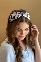 a soft purple fabric headband with black whimsical hat, bat, moon, star, and dot pattern print fabric, wide band silhouette, top know bow detail, lightweight feel, and comfortable slip-on design