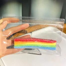 Colorful striped candy in a clear plastic bag held by a hand.
