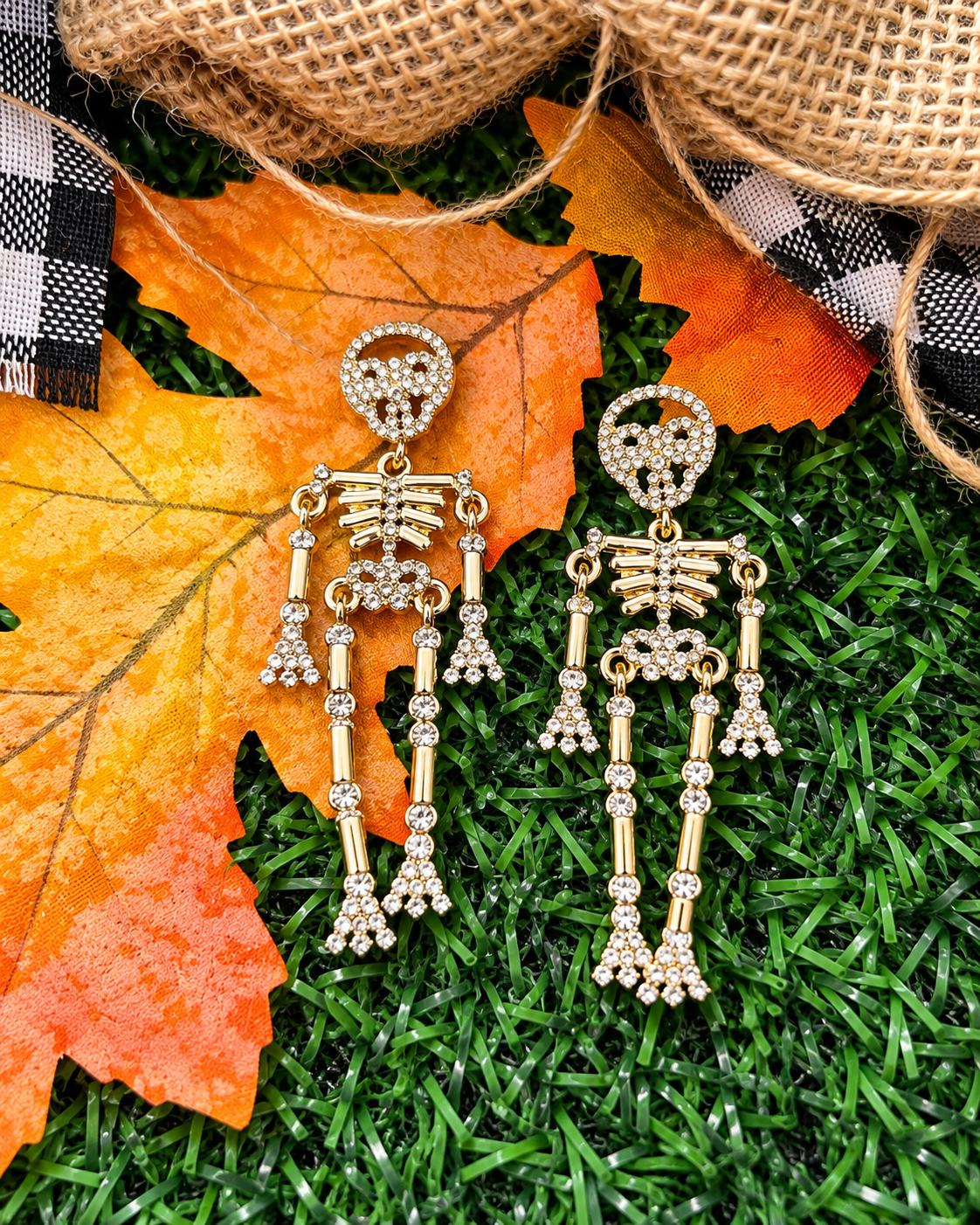 gold-plated post-back skeleton-shaped dangle earrings with rhinestone accents, skull stud tops, articulated bone design, matching barrel backs, and nickel/lead compliant construction in gold