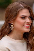 gold-plated post-back skeleton-shaped dangle earrings with rhinestone accents, skull stud tops, articulated bone design, matching barrel backs, and nickel/lead compliant construction in gold
