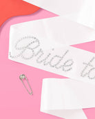 Bride sash with rhinestone accents on a pink background