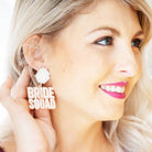 Woman wearing a 'BRIDE SQUAD' earring with a white background