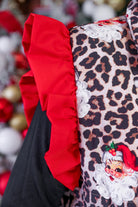 lightweight quilted puffer vest with a playful vintage Santa print on a bold leopard pattern, snap-front closure, flattering fit, practical pockets, and whimsical red ruffle shoulder detail