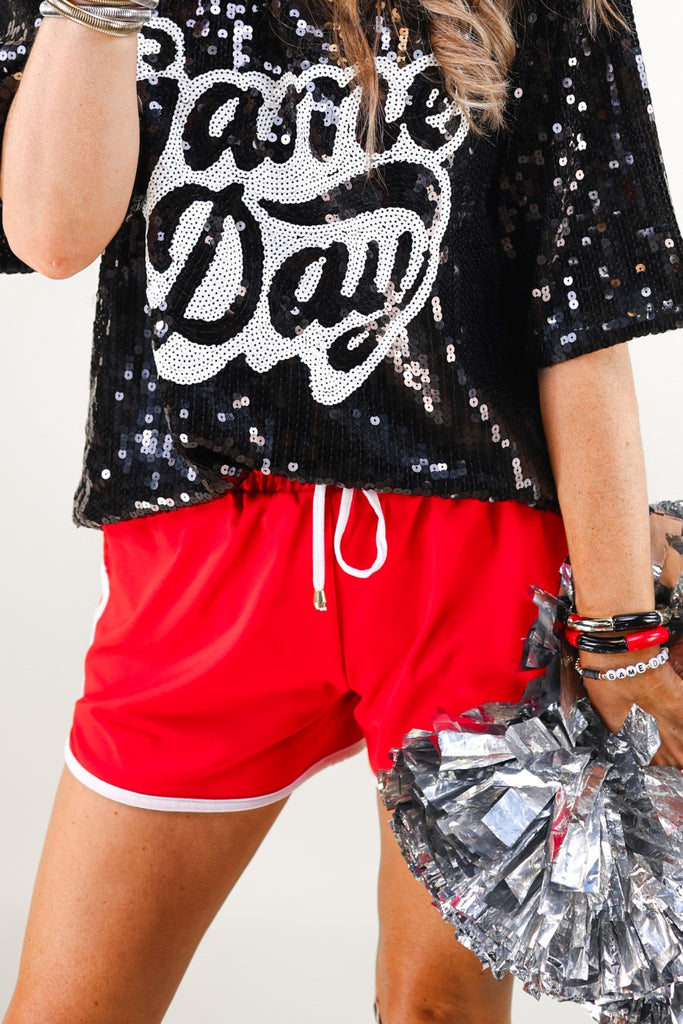 a full sequin design on a solid color with the words GAME DAY on the center front outlined in white sequins, a boxy fit, and a lined interior