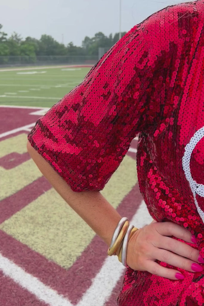 a full sequin design on a solid color with the words GAME DAY on the center front outlined in white sequins, a boxy fit, and a lined interior