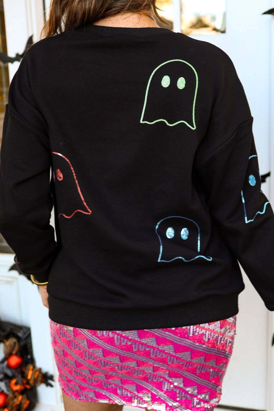 a black long-sleeve pullover crafted from soft fabric with a crew neckline, dropped shoulders, ribbed cuffs, banded hem, relaxed fit, classic sweatshirt silhouette, and colorful sequin ghost outline pattern across the front, back, and sleeve