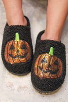 black fuzzy mule slippers with orange sequin jack-o'-lantern appliqués, embroidered green stem accents, cushioned flatbeds, plush lining, open back design, and textured bottoms