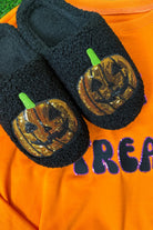 black fuzzy mule slippers with orange sequin jack-o'-lantern appliqués, embroidered green stem accents, cushioned flatbeds, plush lining, open back design, and textured bottoms