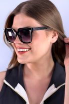 oversized square sunglasses in black
with dark lenses, a raised geometric texture on the temples, and brand name detail (on both the temple and the complimentary black pouch)