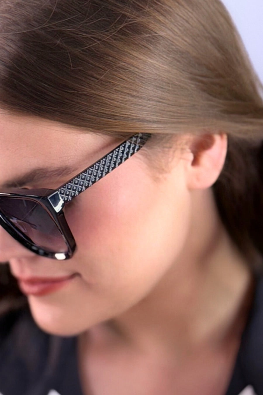 oversized square sunglasses in black with dark lenses, a raised geometric texture on the temples, and brand name detail (on both the temple and the complimentary black pouch)
