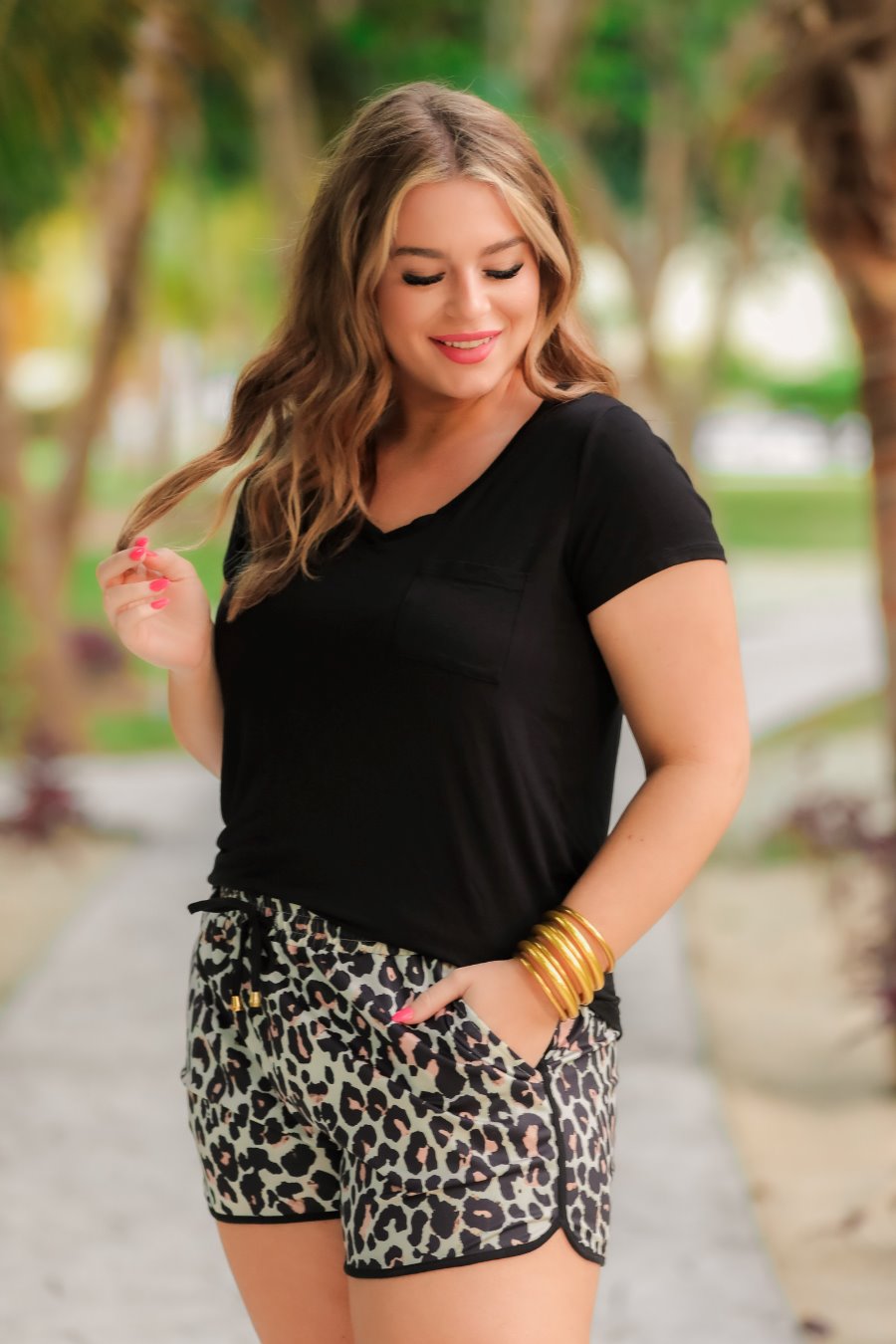mid-rise relaxed fit activewear shorts with side pockets and a tie waist drawstring with gold bead accents, designed on a black and brown leopard pattern print fabric, tan base, and black trim