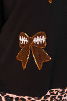 fluttery ruffle short-sleeve top with a mom crop length, sewn-on chenille football bow patches outlined in sequins on a soft, stretch-knit fabric in black