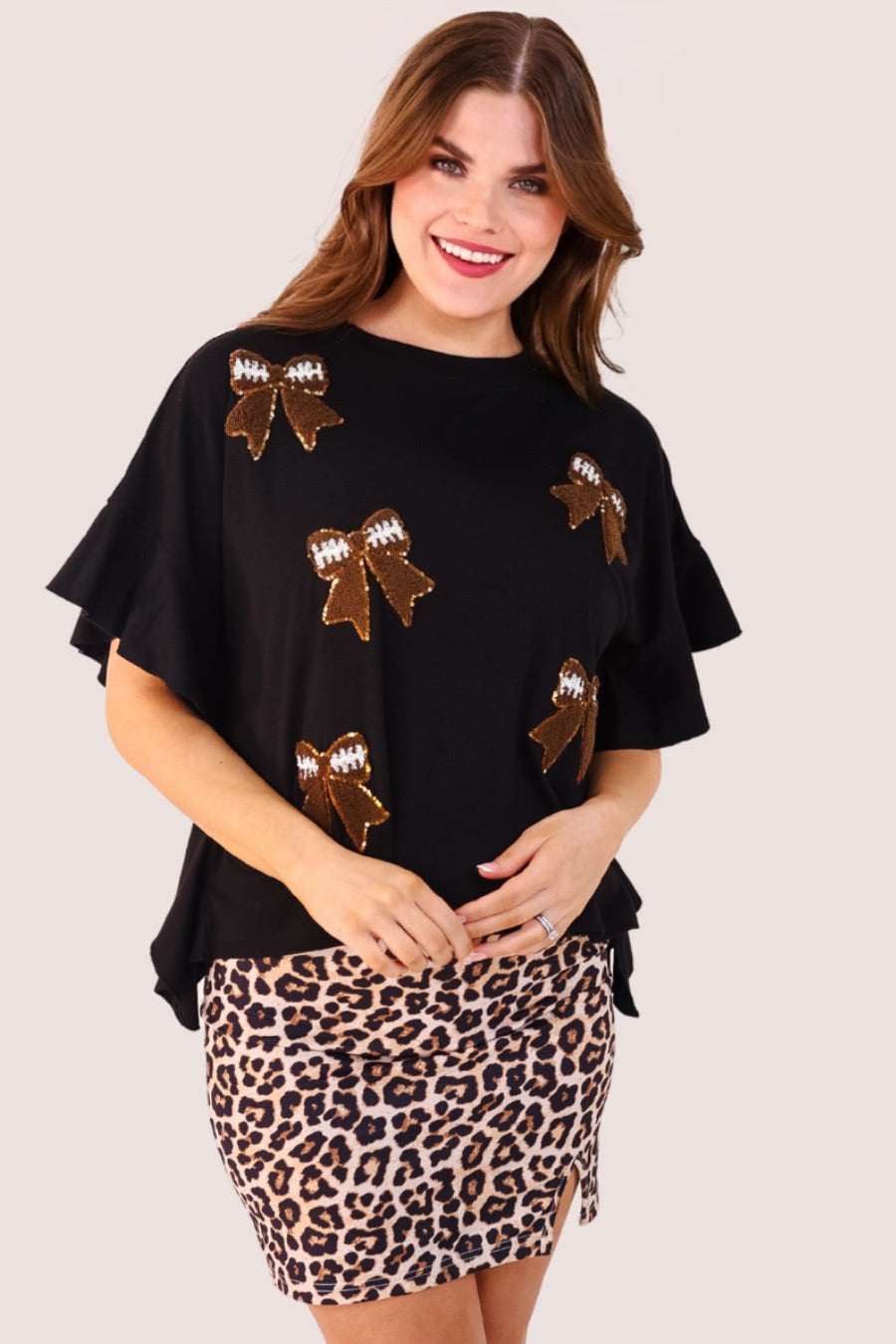 fluttery ruffle short-sleeve top with a mom crop length, sewn-on chenille football bow patches outlined in sequins on a soft, stretch-knit fabric in black