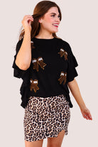fluttery ruffle short-sleeve top with a mom crop length, sewn-on chenille football bow patches outlined in sequins on a soft, stretch-knit fabric in black