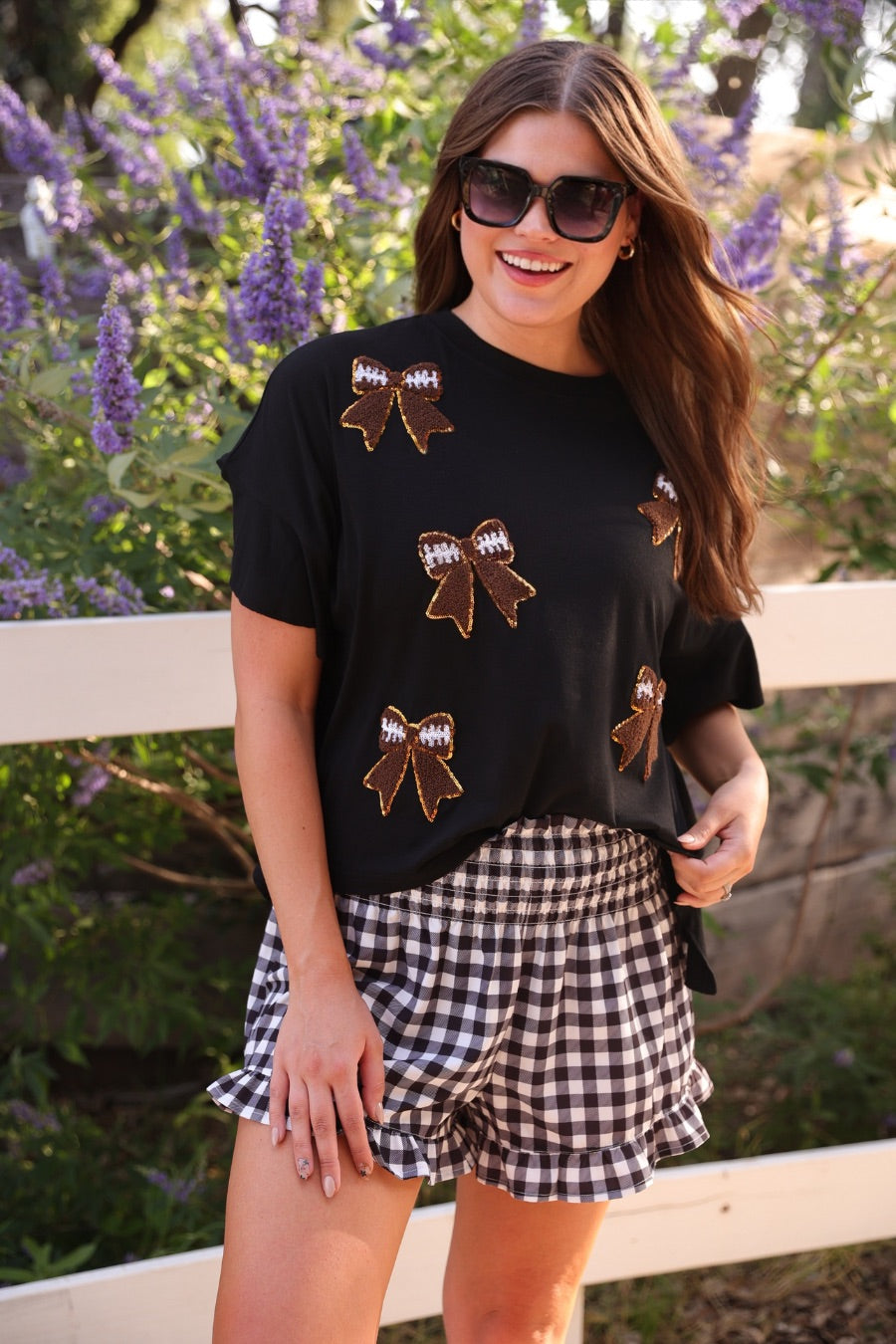 fluttery ruffle short-sleeve top with a mom crop length, sewn-on chenille football bow patches outlined in sequins on a soft, stretch-knit fabric in black