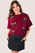 fluttery ruffle short-sleeve top with a mom crop length, sewn-on chenille football bow patches outlined in sequins on a soft, stretch-knit fabric in maroon