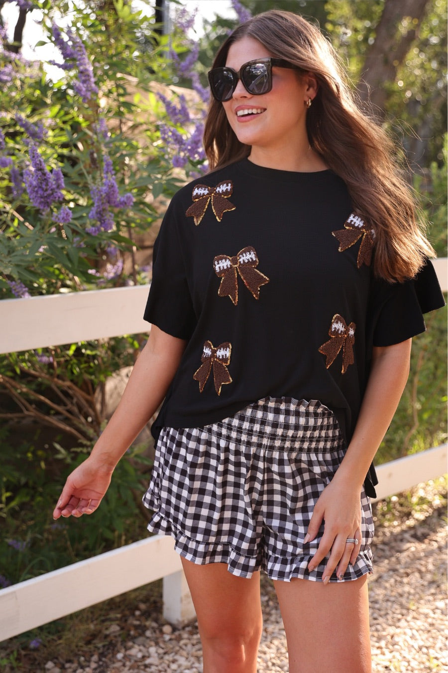 fluttery ruffle short-sleeve top with a mom crop length, sewn-on chenille football bow patches outlined in sequins on a soft, stretch-knit fabric in black