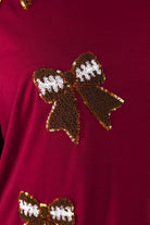 fluttery ruffle short-sleeve top with a mom crop length, sewn-on chenille football bow patches outlined in sequins on a soft, stretch-knit fabric in maroon