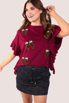fluttery ruffle short-sleeve top with a mom crop length, sewn-on chenille football bow patches outlined in sequins on a soft, stretch-knit fabric in maroon