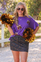 fluttery ruffle short-sleeve top with a mom crop length, sewn-on chenille football bow patches outlined in sequins on a soft, stretch-knit fabric in purple