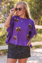fluttery ruffle short-sleeve top with a mom crop length, sewn-on chenille football bow patches outlined in sequins on a soft, stretch-knit fabric in purple