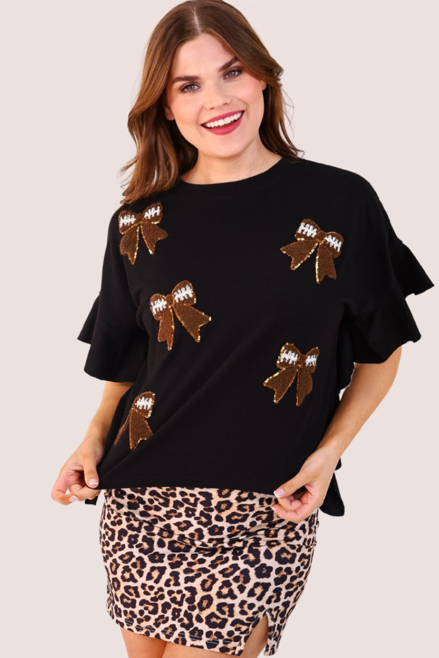 fluttery ruffle short-sleeve top with a mom crop length, sewn-on chenille football bow patches outlined in sequins on a soft, stretch-knit fabric in black