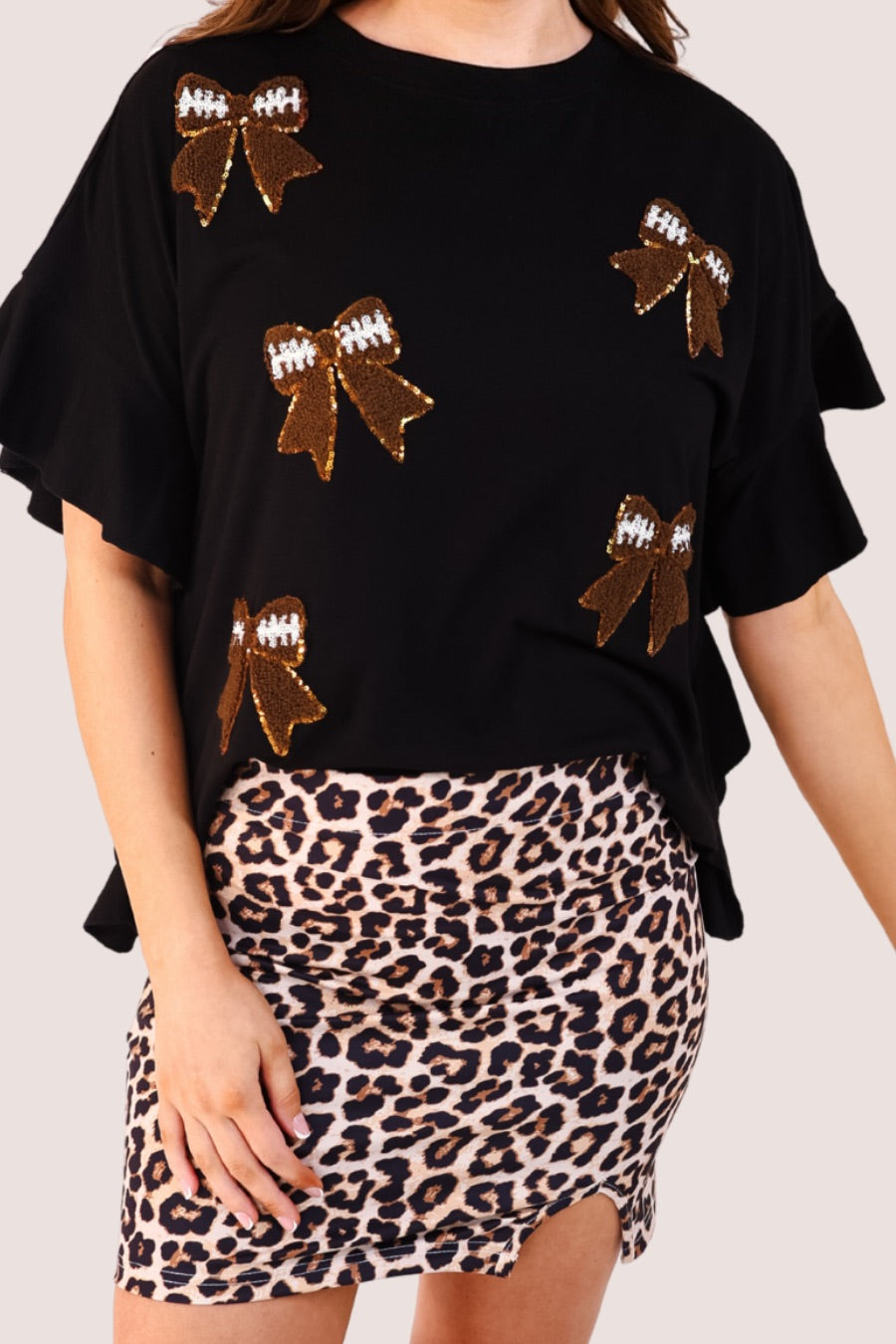 fluttery ruffle short-sleeve top with a mom crop length, sewn-on chenille football bow patches outlined in sequins on a soft, stretch-knit fabric in black