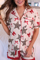 short-sleeve button-down style top with contrast piping and a chest pocket, paired with matching ruffle-trimmed shorts with an elastic waist and decorative tie, designed on a leopard star and red bow pattern print and a cream base, crafted on a soft, lightweight stretchy fabric
