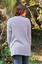  long sleeve cardigan made of a soft knit material with front pockets and a draped open front silhouette that ends in a straight hemline on a grey fabric