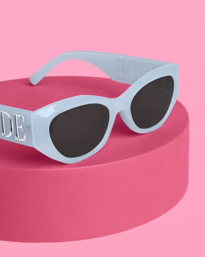 Sunglasses with a light blue frame and dark lenses on a pink platform